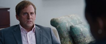 Movie still from “The Big Short” (2015), directed by Adam McKay – A man in a suit sitting in a chair; Close Up shot, Over the shoulder angle