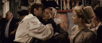 Movie still from “The Black Dahlia” (2006), directed by Brian De Palma – A man and a woman embracing in front of a portrait; Medium shot, Over the shoulder angle