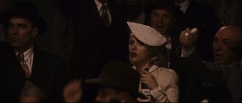 Movie still from “The Black Dahlia” (2006), directed by Brian De Palma – A woman with a hat and a microphone in a crowd; Medium shot, Over the shoulder angle