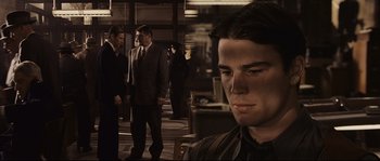 Movie still from “The Black Dahlia” (2006), directed by Brian De Palma – A man in a suit standing next to another man in a suit and tie; Close Up shot, Over the shoulder angle