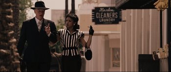 Movie still from “The Black Dahlia” (2006), directed by Brian De Palma – A woman holding a cigarette in her hand and wearing a striped shirt; Medium shot, Low angle