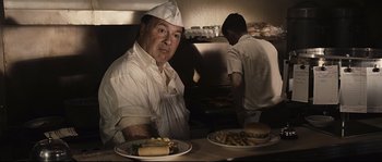 Movie still from “The Black Dahlia” (2006), directed by Brian De Palma – A man sitting in front of a plate of food; Medium shot, Low angle