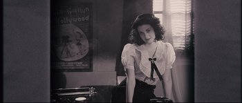Movie still from “The Black Dahlia” (2006), directed by Brian De Palma – A woman in a white blouse is standing in front of a table; Medium shot, High angle