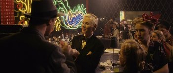 Movie still from “The Black Dahlia” (2006), directed by Brian De Palma – A woman in a suit is talking to two people; Medium shot, Over the shoulder angle