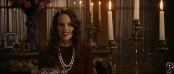 Movie still from “The Black Dahlia” (2006), directed by Brian De Palma – A woman sitting in front of a fireplace holding a wine glass; Medium shot, Over the shoulder angle