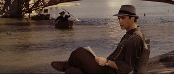 Movie still from “The Black Dahlia” (2006), directed by Brian De Palma – A man sitting on the shore of a lake reading a book; Medium shot, High angle