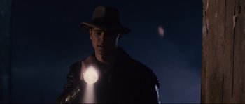 Movie still from “The Black Dahlia” (2006), directed by Brian De Palma – A man wearing a hat and a leather jacket holding a flashlight; Medium shot, Low angle