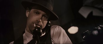 Movie still from “The Black Dahlia” (2006), directed by Brian De Palma – A man in a fedora smoking a cigarette while talking on a phone; Close Up shot, Low angle
