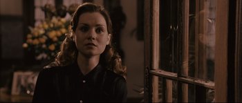 Movie still from “The Black Dahlia” (2006), directed by Brian De Palma – A young woman in a black shirt is standing in front of a window; Close Up shot, Over the shoulder angle