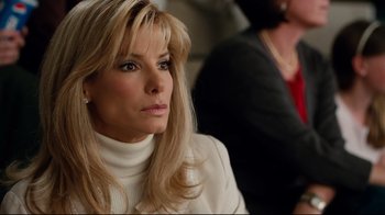 Movie still from “The Blind Side” (2009), directed by John Lee Hancock – A woman in a white sweater looks to her left; Close Up shot, Over the shoulder angle