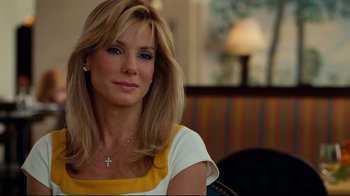 Movie still from “The Blind Side” (2009), directed by John Lee Hancock – A woman sitting in front of a window with a cross on her neck; Close Up shot, Over the shoulder angle