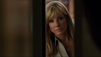 Movie still from “The Blind Side” (2009), directed by John Lee Hancock – A beautiful woman with long blonde hair and a cross necklace; Close Up shot, Over the shoulder angle