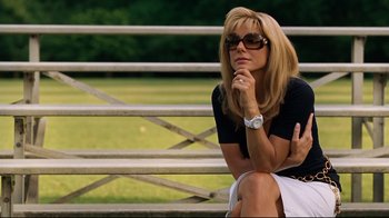 Movie still from “The Blind Side” (2009), directed by John Lee Hancock – A woman sitting on a bench with her hand under her chin; Medium shot, Low angle