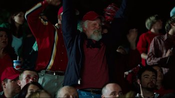 Movie still from “The Blind Side” (2009), directed by John Lee Hancock – An older man with a red hat is holding his hands up in the air; Medium shot, Low angle