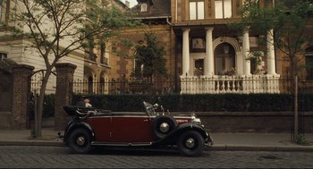 Movie still from “The Boy in the Striped Pajamas” (2008), directed by Mark Herman – An old car is parked on the side of the road; Extreme Wide shot, High angle