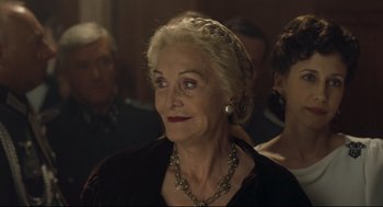 Movie still from “The Boy in the Striped Pajamas” (2008), directed by Mark Herman – An older woman wearing a black dress and a necklace; Close Up shot, Over the shoulder angle