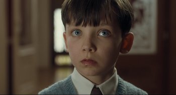 Movie still from “The Boy in the Striped Pajamas” (2008), directed by Mark Herman – A young boy with blue eyes wearing a sweater and tie; Close Up shot, Low angle