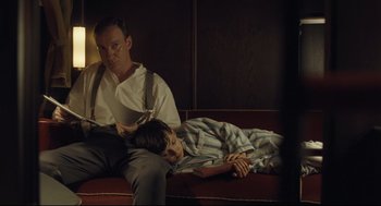 Movie still from “The Boy in the Striped Pajamas” (2008), directed by Mark Herman – A man sitting on a couch next to a young boy; Medium shot, Low angle