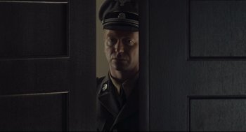 Movie still from “The Boy in the Striped Pajamas” (2008), directed by Mark Herman – A man in a military uniform is looking through a door; Medium shot, Over the shoulder angle