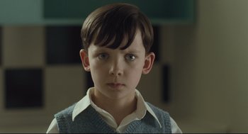 Movie still from “The Boy in the Striped Pajamas” (2008), directed by Mark Herman – A young boy in a white collared shirt and a blue vest; Close Up shot, Over the shoulder angle
