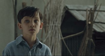 Movie still from “The Boy in the Striped Pajamas” (2008), directed by Mark Herman – A young boy is standing in front of a building; Close Up shot, Over the shoulder angle