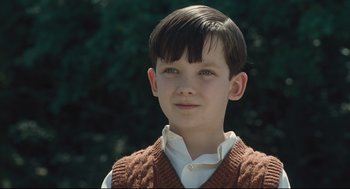 Movie still from “The Boy in the Striped Pajamas” (2008), directed by Mark Herman – A young boy wearing a brown sweater vest and a white shirt; Close Up shot, High angle