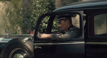 Movie still from “The Boy in the Striped Pajamas” (2008), directed by Mark Herman – A man sitting in the driver's seat of an old car; Medium shot, High angle