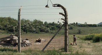 Movie still from “The Boy in the Striped Pajamas” (2008), directed by Mark Herman – A man is walking in a field near a fence; Extreme Wide shot, High angle