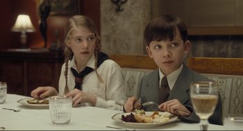 Movie still from “The Boy in the Striped Pajamas” (2008), directed by Mark Herman – A boy and a girl sitting at a dinner table; Medium shot, Over the shoulder angle