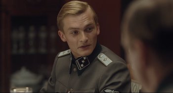 A man in a military uniform is looking at the camera