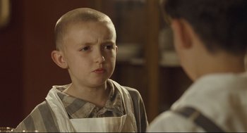 Movie still from “The Boy in the Striped Pajamas” (2008), directed by Mark Herman – A young boy with a shaved head looks at a younger boy; Close Up shot, Over the shoulder angle