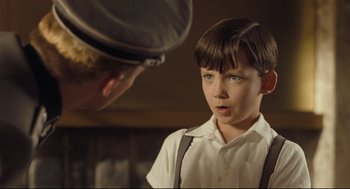 Movie still from “The Boy in the Striped Pajamas” (2008), directed by Mark Herman – A young boy in a white shirt is looking at a man in a black hat; Close Up shot, Over the shoulder angle
