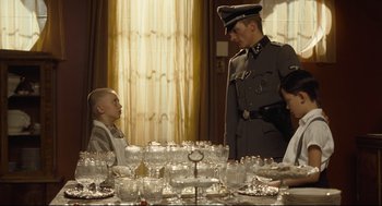 Movie still from “The Boy in the Striped Pajamas” (2008), directed by Mark Herman – A man in uniform standing next to a woman and a child; Medium shot, Over the shoulder angle