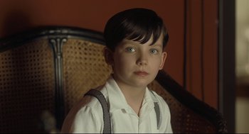 Movie still from “The Boy in the Striped Pajamas” (2008), directed by Mark Herman – A young boy wearing a white shirt and black suspenders; Close Up shot, High angle