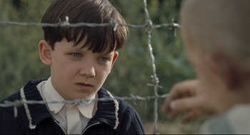 Movie still from “The Boy in the Striped Pajamas” (2008), directed by Mark Herman – A young boy looking through a barbed wire fence; Close Up shot, Over the shoulder angle