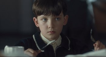 Movie still from “The Boy in the Striped Pajamas” (2008), directed by Mark Herman – A young boy holding a pair of scissors in his hand; Close Up shot, Over the shoulder angle