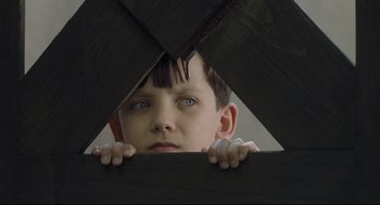 Movie still from “The Boy in the Striped Pajamas” (2008), directed by Mark Herman – A young boy is looking through a wooden fence; Close Up shot, High angle