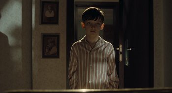 Movie still from “The Boy in the Striped Pajamas” (2008), directed by Mark Herman – A young boy standing in front of a bathroom mirror; Medium shot, Over the shoulder angle