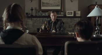 Movie still from “The Boy in the Striped Pajamas” (2008), directed by Mark Herman – A man sitting at a table in front of other people; Medium shot, Over the shoulder angle
