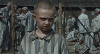 Movie still from “The Boy in the Striped Pajamas” (2008), directed by Mark Herman – A young boy in a striped shirt in front of a group of men; Medium shot, High angle