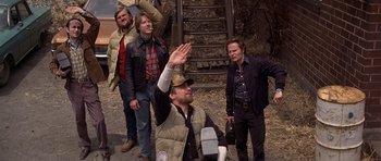 Movie still from “The Deer Hunter” (1978), directed by Michael Cimino – A group of men standing next to each other on a dirt road; Medium shot, Low angle
