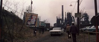 Movie still from “The Deer Hunter” (1978), directed by Michael Cimino – A group of people standing next to an old car; Extreme Wide shot, High angle