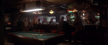 Movie still from “The Deer Hunter” (1978), directed by Michael Cimino – A group of people sitting around a pool table in a bar; Wide shot, Over the shoulder angle