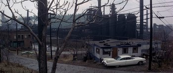 Movie still from “The Deer Hunter” (1978), directed by Michael Cimino – An old car parked in front of an abandoned building; Extreme Wide shot, High angle