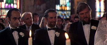 Movie still from “The Deer Hunter” (1978), directed by Michael Cimino – A man in a tuxedo standing in front of a group of people; Close Up shot, Over the shoulder angle