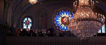 Movie still from “The Deer Hunter” (1978), directed by Michael Cimino – A group of people sitting at a table in front of a stained - glass clock; Extreme Wide shot, Low angle