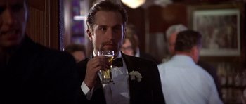 Movie still from “The Deer Hunter” (1978), directed by Michael Cimino – A man in a tuxedo drinking a glass of wine; Close Up shot, Over the shoulder angle