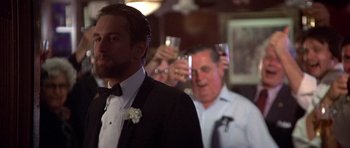 Movie still from “The Deer Hunter” (1978), directed by Michael Cimino – A man in a suit and tie holding a wine glass; Close Up shot, Over the shoulder angle