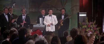 Movie still from “The Deer Hunter” (1978), directed by Michael Cimino – A group of men in tuxedos performing on a stage; Medium shot, Low angle