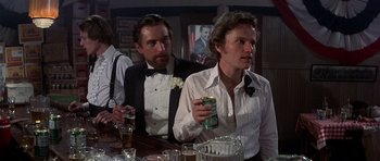 Movie still from “The Deer Hunter” (1978), directed by Michael Cimino – Two men in tuxedos are sitting at a bar drinking beers; Medium shot, Over the shoulder angle
